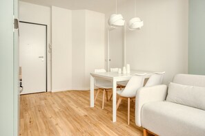Ein modernes, minimalistisches Zimmer mit Holzboden, weißen Möbeln und Pendelleuchten.