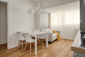 Ein modernes, minimalistisches Wohnzimmer mit Essbereich, einer Couch und einem Fernseher.