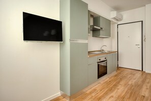 Eine Küche mit Backofen, Spüle und einem flachbildfernseher an der Wand.