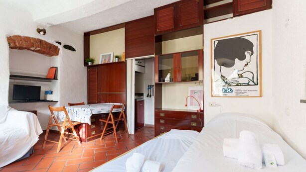 A hotel room with a bed, a small table, a chair, and a kitchenette area. - GuestHost - A practical 20 square meters studio apartment, perfect for two people, located on the ground floor of a building with a private entrance.The property is located in the Nervi neighborhood, just 400 meters from Caprafico beach, making it easy f (Genoa)