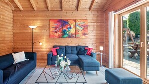 A wooden interior with a sectional sofa, a glass coffee table, and a painting on the wall. - Holiday Home 'Landhaus-Eifelhöhe' with Private Terrace, Private Garden and Wi-Fi (Schüller)