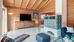 A wooden interior with a fireplace, a television, and a sofa. - Holiday Home 'Landhaus-Eifelhöhe' with Private Terrace, Private Garden and Wi-Fi (Schüller)