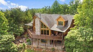 A two-story log cabin with a balcony, surrounded by dense forest. - Among the Clouds: Stay High Above It All (Gatlinburg)