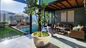 Una sala de estar moderna con un amplio ventanal, una piscina y mobiliario exterior.
