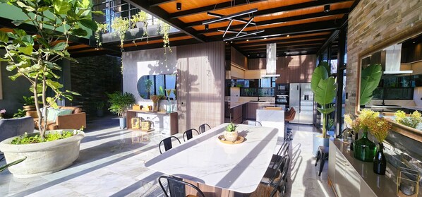 A modern kitchen with a large island, built-in appliances, and a dining area with a marble table and chairs. - w Private 4BR Getaway With Pool Cinema (Salas)