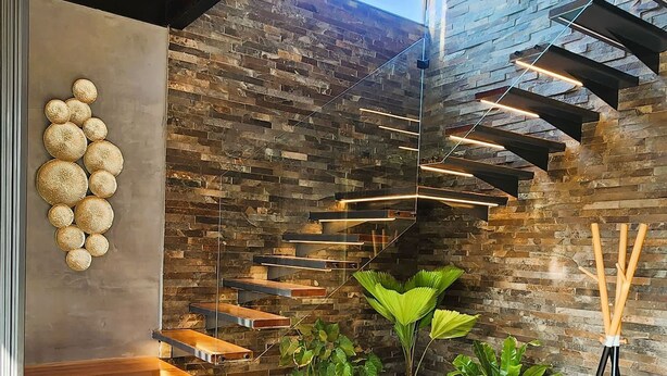 Un interior moderno con techo de madera, pared de piedra y una escalera.