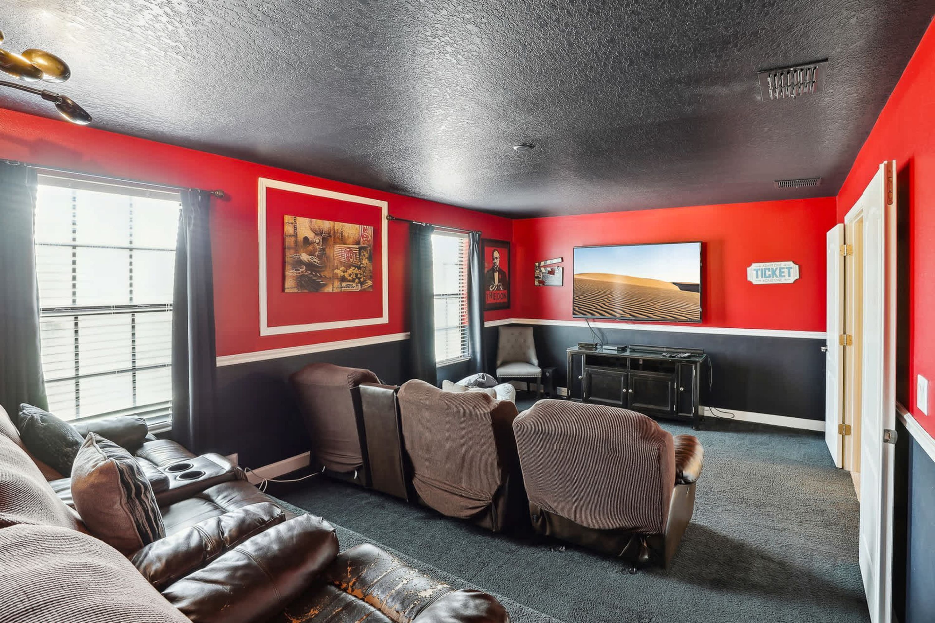 Une pièce aux couleurs rouge et noir, avec des canapés en cuir, un bureau et une grande fenêtre.