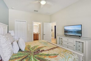 A bedroom with a bed, a television, a ceiling fan, and a view of a kitchen and bathroom through an open door. - Upstay Family Home w Pool Cinema Championsgate (Davenport)