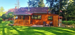 Une cabane en bois avec un porche, une cheminée et une petite terrasse.