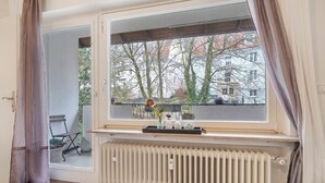 Een kamer met een groot raam, een radiator eronder en een deur naar buiten.