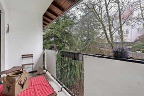 Een balkon met een rood geruit tafelkleed, een houten bankje en een decoratieve houten doos met een rendiermodel.