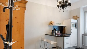 A kitchen with a black and white checkered floor, a wooden cabinet, a chandelier, and a microwave. - Apartment, 33 sqm, up to 2 guests with private terrace and Wi-Fi (Baden-Baden)
