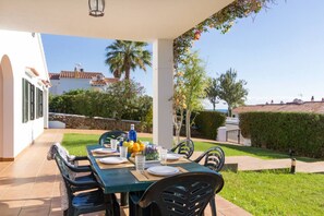 Un espace de restauration en plein air avec une table dressée pour quatre personnes, entourée de chaises.