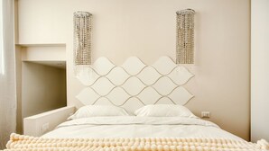 A bed with a diamond-patterned headboard, a fluffy white blanket, and two wall-mounted light fixtures. - Hostmate - Milano - Imperia's Pearl - Romolo IULM (Milano)
