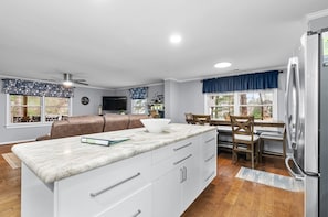 A modern kitchen with white cabinetry, a marble countertop, and a built-in refrigerator. - Lizard Creek Retreat | Pet-Friendly | New Boathouse (Littleton)