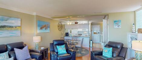 A living room with leather sofas, a glass coffee table, and artwork on the walls.