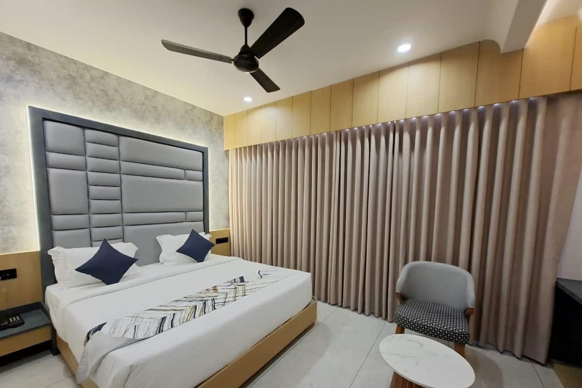 A modern hotel room with a large bed, a ceiling fan, a small round table, and a chair.