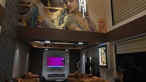 A spacious living area with a large mural, a chandelier, and a flat-screen TV. - White Panda Hotels Shree Radhe (Dwarka)