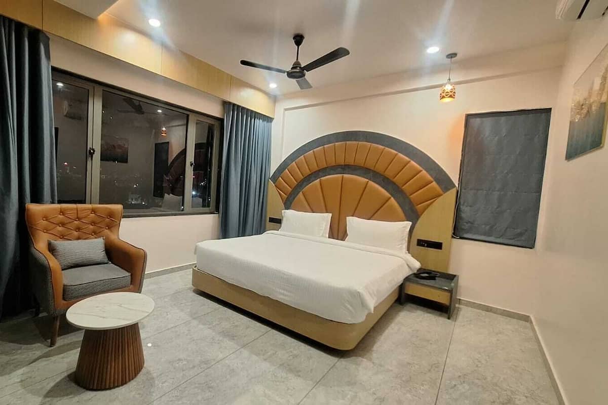 A bedroom with a bed, a chair, a round table, and a ceiling fan.