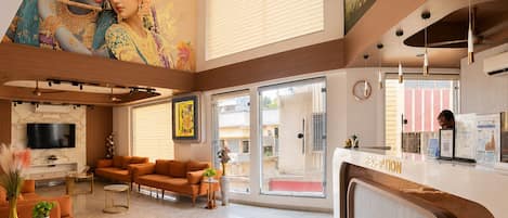A hotel lobby with a reception desk, seating area, and a mural on the wall.