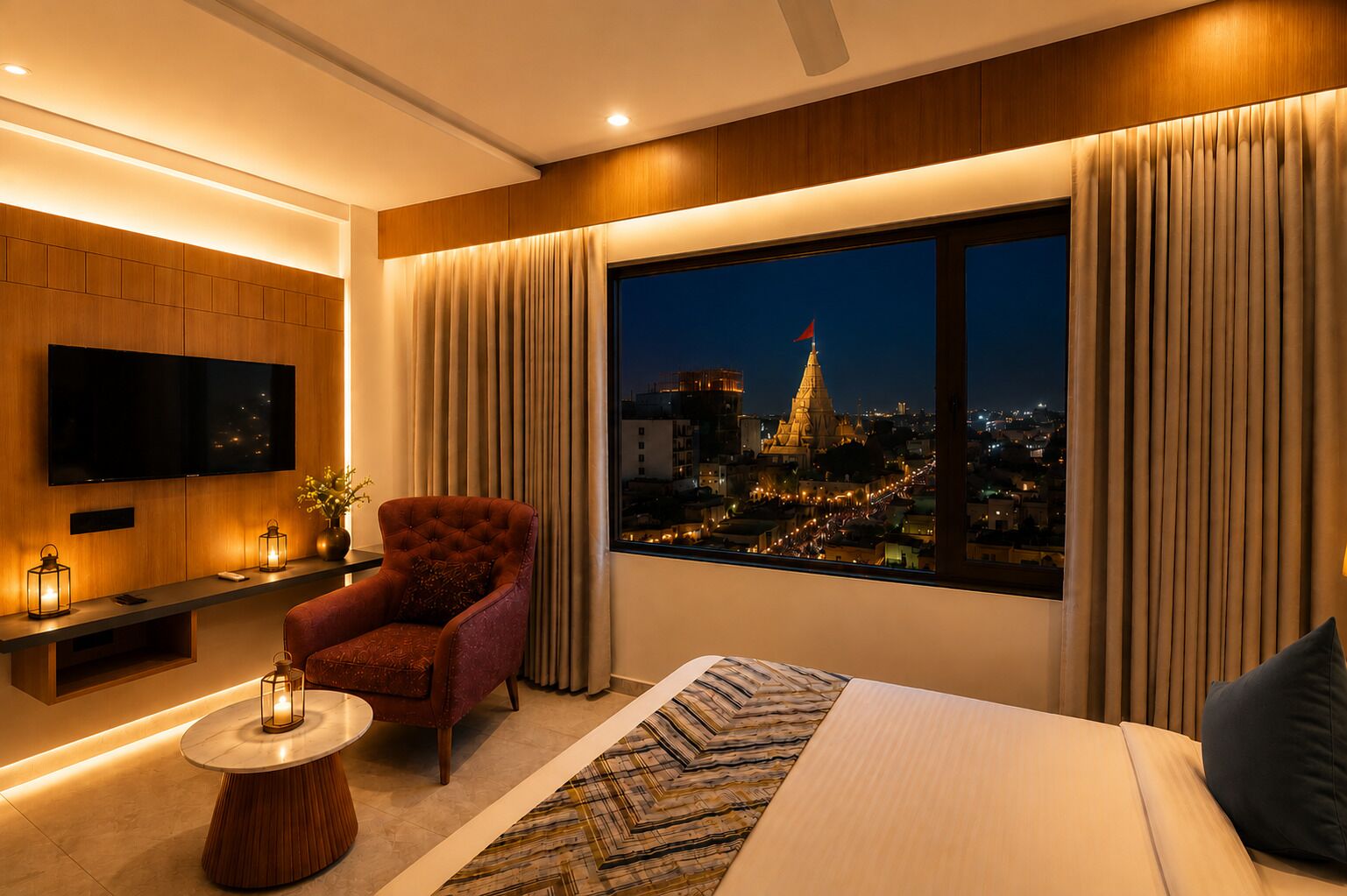 A modern hotel room with a large window, a comfortable bed, a red armchair, a small round table with a lamp, and a flat-screen TV mounted on the wall.