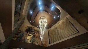 A modern interior with a decorative ceiling, a staircase, and a large window with blinds. - White Panda Hotels Shree Radhe (Dwarka)