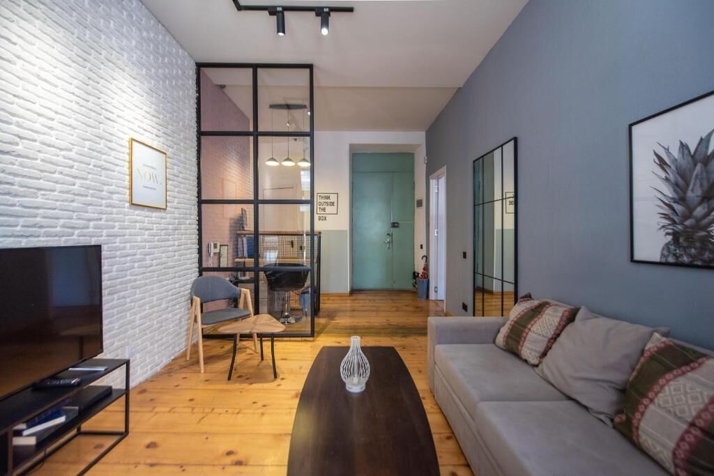 Una sala de estar moderna con televisor, sofá, mesa de centro y comedor con una silla y una mesa.