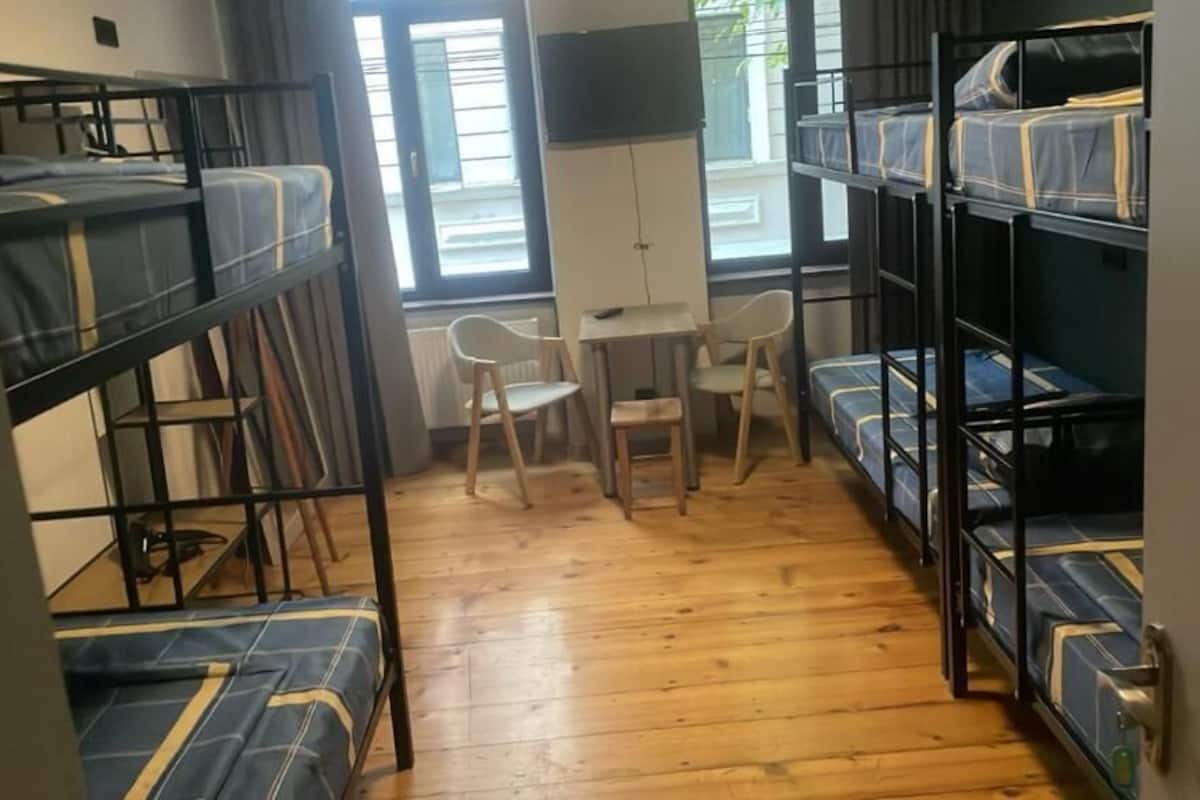 A dormitory room with bunk beds, a small table, and chairs.