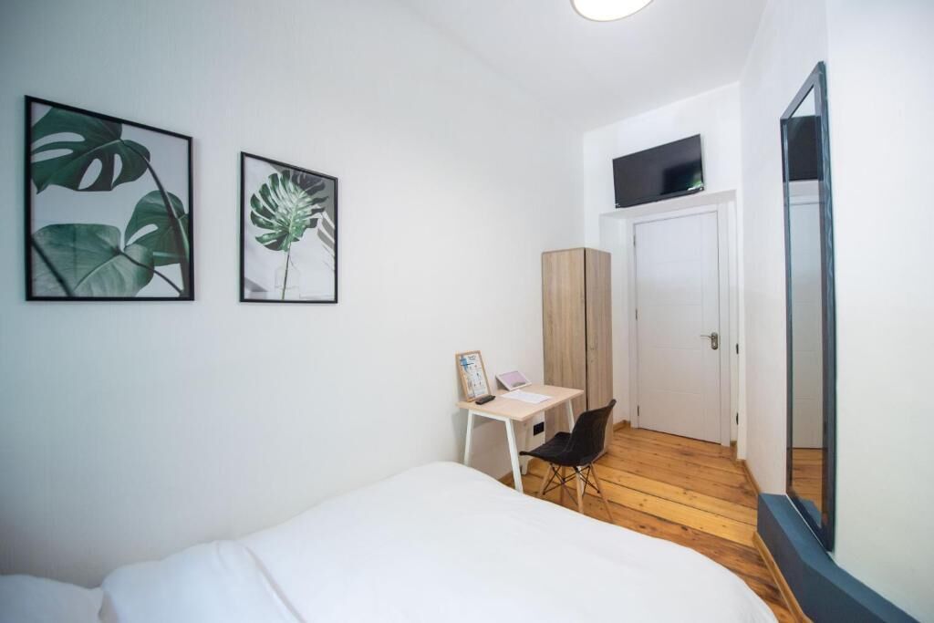 Une chambre à coucher avec un lit, un bureau, une chaise et deux tableaux encadrés accrochés au mur.