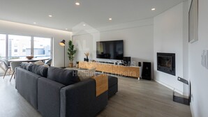 Ein modernes Wohnzimmer mit grauem Sofa, einem Holztischchen, einem Fernseher und einem Kamin.