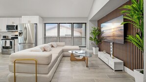 Una sala de estar moderna con un sofá modular, una mesa de centro de vidrio y un televisor de pantalla plana montado en una pared de madera.