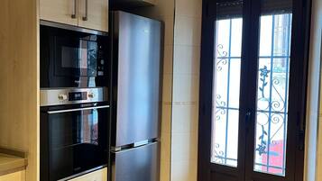 A compact kitchen with a built-in microwave, oven, and refrigerator.