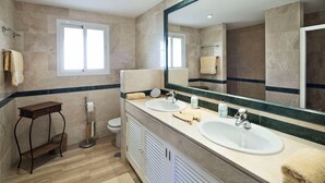Een moderne badkamer met twee wastafels, een grote spiegel en een raam.
