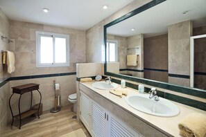 Een moderne badkamer met twee wastafels, een grote spiegel en een raam.