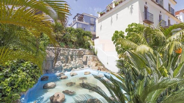 Una piscina con acqua cristallina, rocce e vegetazione lussureggiante.