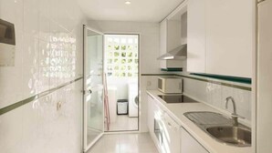 Una cocina moderna con armarios blancos, un lavamanos de acero inoxidable y un microondas.