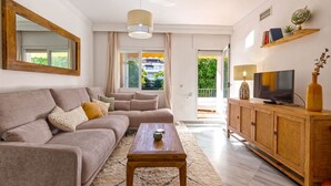 Una sala de estar con sofá, mesa de centro, televisor y un mueble de madera.
