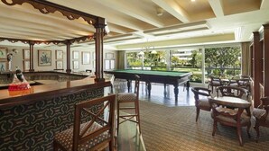 Un espace piscine comprenant un bar, une table de billard et des sièges.