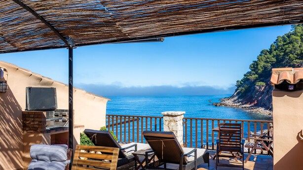 A terrace with outdoor seating, a grill, and a view of the sea.