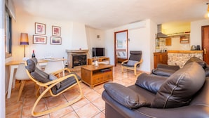 A living room with a fireplace, leather sofa, wooden coffee table, and a dining area with chairs and a table.