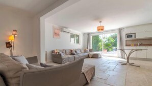 Een moderne woonkamer met een bank, salontafel en een lamp. Er is een keukenhoek met een magnetron en een spoelbak.