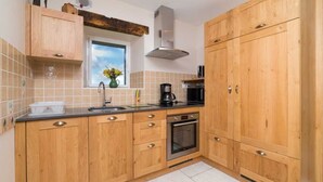 Eine Küche mit Holzausstattung, einer Edelstahl-Spüle, einer Kaffeemaschine und einem eingebauten Backofen.