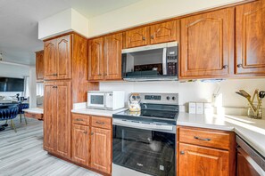A kitchen with wooden cabinets, a microwave, a stove, and an oven. - Steps to Golf & Greenbelt! Elegant Scottsdale Unit (Scottsdale)
