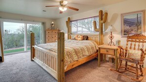 Een slaapkamer met een houten bed, een bureau, een schommelstoel en een plafondventilator.