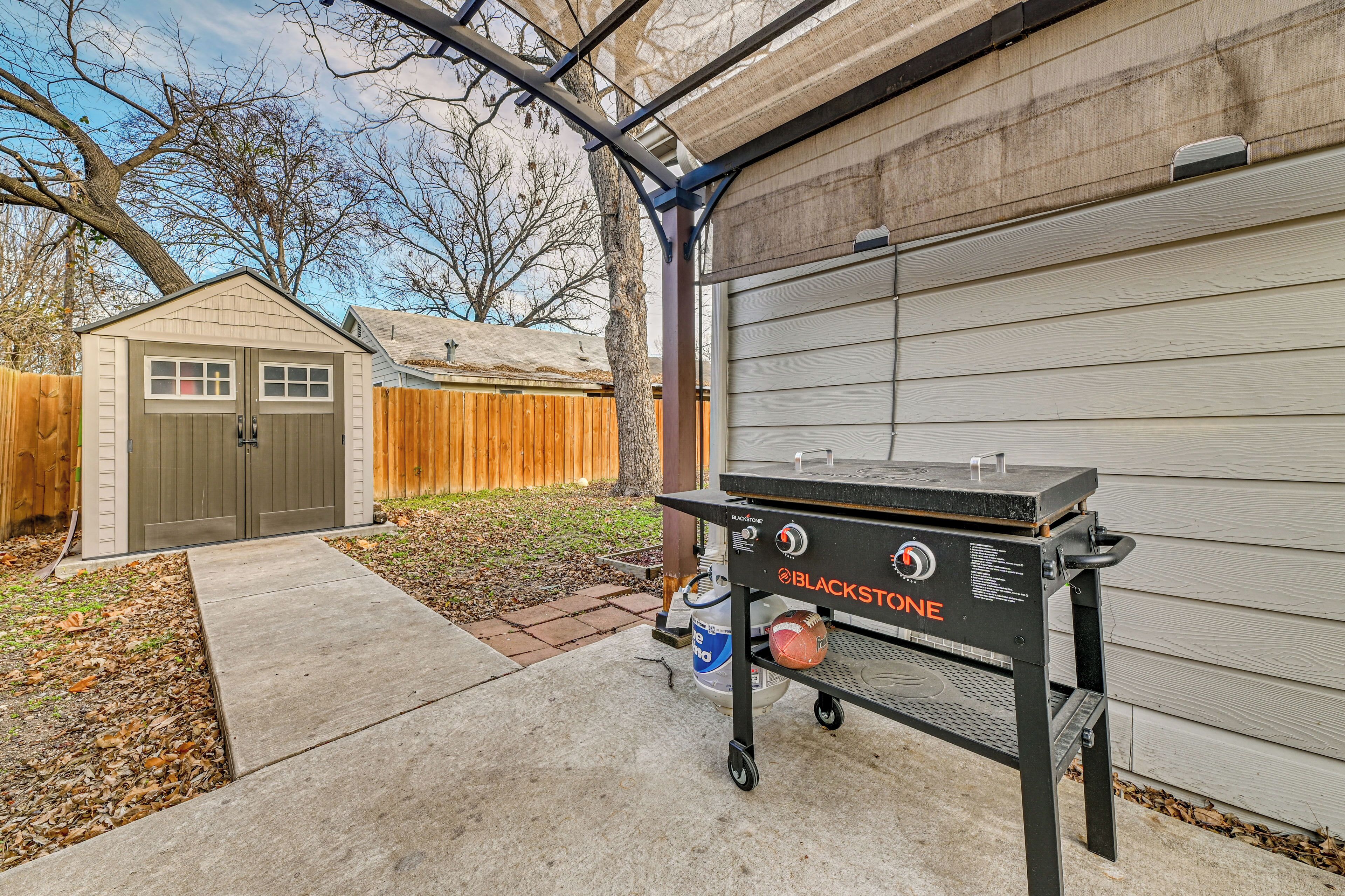 A backyard with a barbecue grill, a shed, and a house.