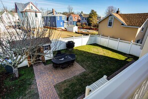 A backyard with a brick patio, a barbecue grill, and a table set up for outdoor dining. - Walk to Broadway Beach! Cape May Getaway w/ Grill (Cape May)