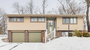 A two-story house with a garage, a front porch, and a snow-covered driveway.