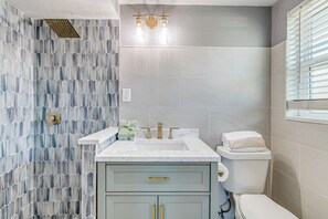 A bathroom with a hexagonal patterned wall, a white sink with gold fixtures, a toilet, and a window with blinds. - 6 Mi to Hudson Beach! Pet-friendly Retreat w/ Yard (Port Richey)