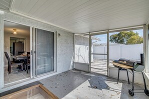 A covered patio area with a sliding glass door leading to a dining area, a grill on a cart, and a view of a backyard fence. - 6 Mi to Hudson Beach! Pet-friendly Retreat w/ Yard (Port Richey)