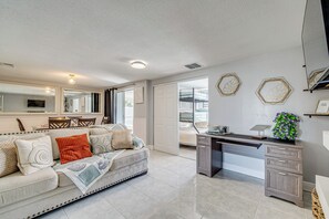 A modern living room with a sofa, a desk, and a large mirror. - 6 Mi to Hudson Beach! Pet-friendly Retreat w/ Yard (Port Richey)